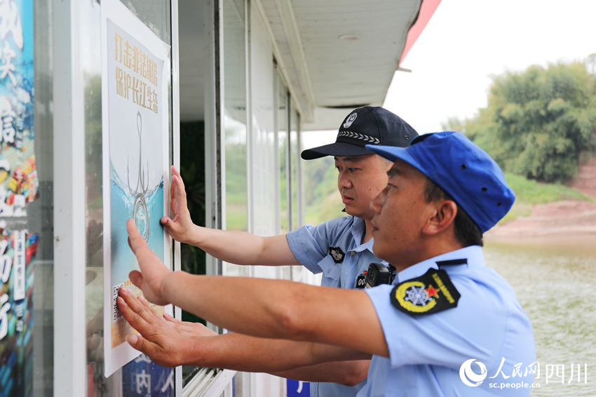 长江航运公安民警与渔政协助巡护队员一同张贴“禁捕”宣传海报。人民网 赵祖乐摄