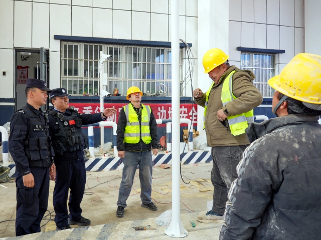 图为检查站民警提醒正在搭建无感知系统的施工人员注意安全_副本.jpg